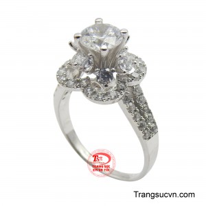 Viên đá chủ CZ trong suốt và lấp lánh như giọt sương mai, được bao bọc bởi một vòng xoáy đá quý nhỏ hơn, tạo nên một thiết kế độc đáo, đầy tinh tế.