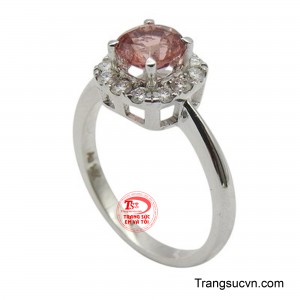 Mặt nhẫn nổi bật với viên Spinel thiên nhiên màu hồng phấn ấm áp, được cắt giác rực rỡ và đặt tại vị trí trung tâm.