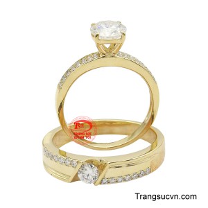 Nhẫn nữ nổi bật với viên đá chủ lớn cắt tròn cùng đường viền nạm đá rực rỡ, trong khi nhẫn nam có chi tiết đá đơn tinh xảo, thể hiện sự hòa hợp và tôn vinh lẫn nhau.