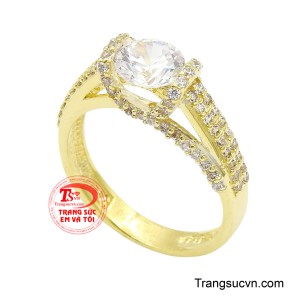 Bao quanh là những viên đá kết lấp lánh được đính tỉ mỉ dọc theo thân nhẫn, tạo nên hiệu ứng ánh sáng lan tỏa mềm mại mà rực rỡ. 