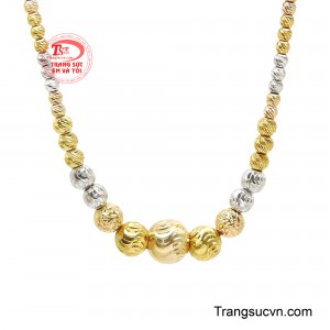 Điểm nhấn trung tâm là cụm bi vàng kích thước lớn được chế tác tinh xảo với họa tiết uốn lượn độc đáo, tượng trưng cho sự chuyển động không ngừng và nguồn năng lượng tích cực. 