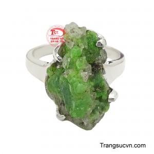 Tâm điểm của chiếc nhẫn là viên tinh thể emerald với màu xanh tươi mát, phản chiếu ánh sáng qua các mặt cắt sắc nét, tạo nên hiệu ứng lấp lánh đầy mê hoặc.