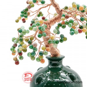 Thân cây được tạo hình uốn lượn bằng dây đồng ánh kim, mang dáng thế mềm mại nhưng vững chắc, tạo cảm giác như một cổ thụ đang vươn mình phát triển.