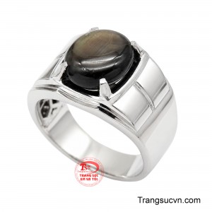 Tâm điểm là viên sapphire đen dạng cabochon oval, sở hữu sắc trầm sâu cùng ánh lụa mềm mại, tạo chiều sâu cuốn hút mỗi khi bắt sáng.