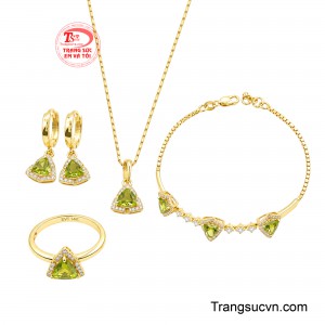 Bộ trang sức gồm dây chuyền, bông tai, nhẫn và lắc tay được thiết kế đồng điệu, nổi bật với những viên đá Peridot giác cắt tam giác độc đáo, bao quanh bởi các viên đá cz lấp lánh, tạo hiệu ứng bắt sáng cuốn hút.