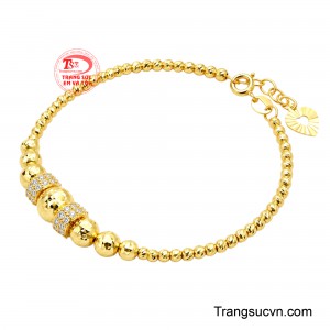 Điểm nhấn trung tâm là cụm bi vàng kích thước lớn kết hợp hai đai đính đá sáng, tạo nên vẻ sang trọng và nổi bật. 
